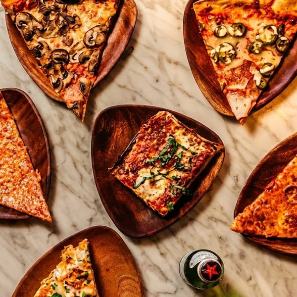 Assortment of pizza slices, including cheese, mushroom, pepperoni, and jalapeño, on wooden plates.